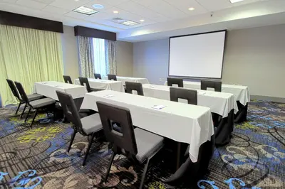 a conference room with tables and chairs and a whiteboard at Hilton Garden Inn Westbury in Westbury