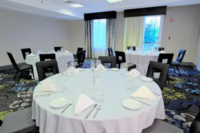 a conference room with tables and chairs with white tablecloths at Hilton Garden Inn Westbury in Westbury