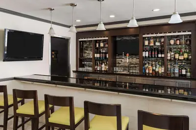 a bar with yellow chairs and a tv in a room at Hilton Garden Inn Westbury in Westbury