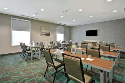 a conference room with tables and chairs and a flat screen tv at Home2 Suites by Hilton Queensbury Lake George in Queensbury
