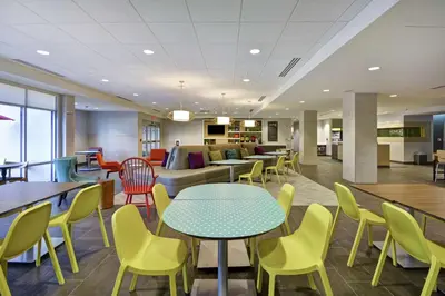 a lobby with tables and chairs and a couch at Home2 Suites by Hilton Queensbury Lake George in Queensbury