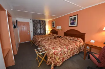 a hotel room with two beds and a desk at Williamstown Motel in Williamstown