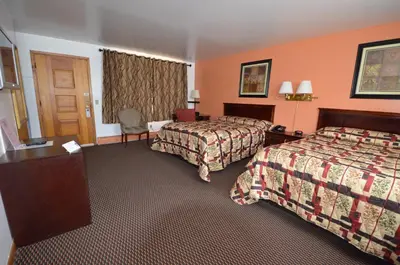 a hotel room with two beds and a desk at Williamstown Motel in Williamstown