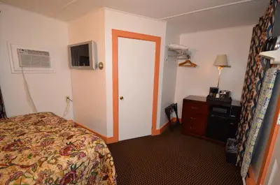 a hotel room with a bed and a dresser and a door at Williamstown Motel in Williamstown