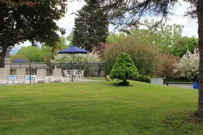 a table and chairs with an umbrella on a lawn at Berkshire Inn in Pittsfield