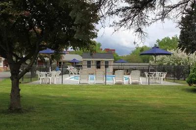 a group of chairs and a pool with an umbrella at Berkshire Inn in Pittsfield