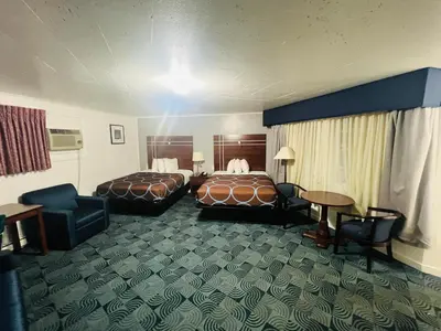 a hotel room with two beds and a table and chairs at Berkshire Inn in Pittsfield