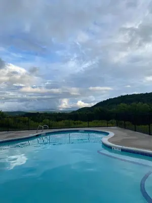a swimming pool with a view of the mountains at August Lodge Cooperstown in Hartwick Seminary