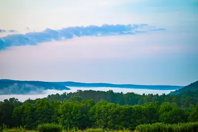 a view of a valley of trees and clouds at August Lodge Cooperstown in Hartwick Seminary