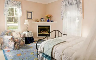 a bedroom with a bed and a chair and a fireplace at Hampton Terrace Inn in Lenox