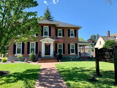 a brick house with a sign in front of it at Grand Colonial Bed and Breakfast in Herkimer