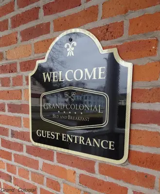 a sign for a grand colonial guest entrance on a brick wall at Grand Colonial Bed and Breakfast in Herkimer