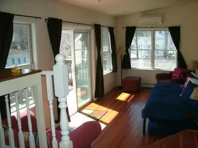 a living room with a blue couch and windows at Townhouse W Private Deck & Mt View in Windham