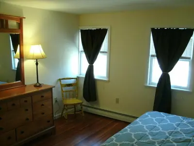 a bedroom with a bed and a dresser and two windows at Townhouse W Private Deck & Mt View in Windham