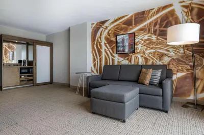 a living room with a couch and a table at Cambria Hotel West Orange in West Orange