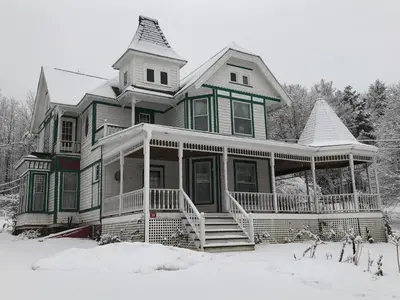 a large house with snow on the ground at Antique Rose Inn Windham in Windham