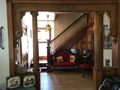 a living room with a staircase and a red chair at Antique Rose Inn Windham in Windham