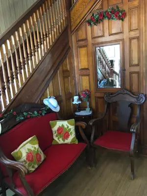 a stairway with a red couch and two chairs at Antique Rose Inn Windham in Windham