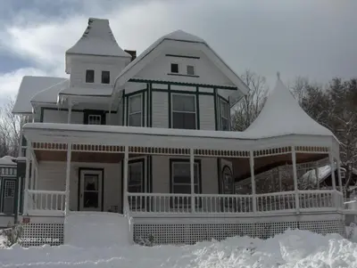 a large house with snow on the ground at Antique Rose Inn Windham in Windham