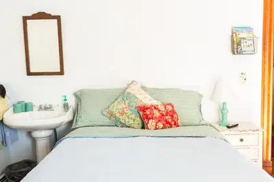a bedroom with a bed with pillows and a sink at Antique Rose Inn Windham in Windham