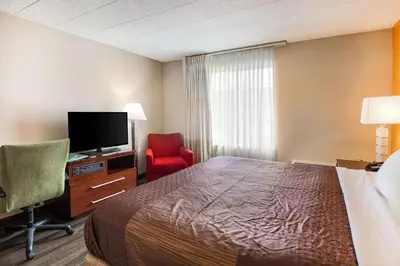 a hotel room with a bed and a tv and a chair at Fairmount Inn & Suites - Stroudsburg, Poconos in Delaware Water Gap