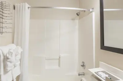a white bathroom with a shower and a sink at Super 8 by Wyndham Schenectady/Albany Area in Schenectady