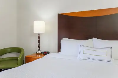 a bedroom with a bed and a green chair at Fairfield Inn & Suites by Marriott Mahwah in Mahwah
