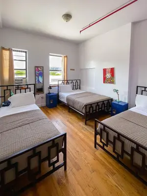 a room with three beds and two windows at NY Moore Hostel in Brooklyn