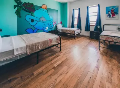 a bedroom with two beds and a wall with a cartoon at NY Moore Hostel in Brooklyn