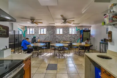 a kitchen with tables and people sitting at tables at NY Moore Hostel in Brooklyn