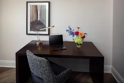 a desk with a laptop and a vase of flowers at Hilton Albany in Albany