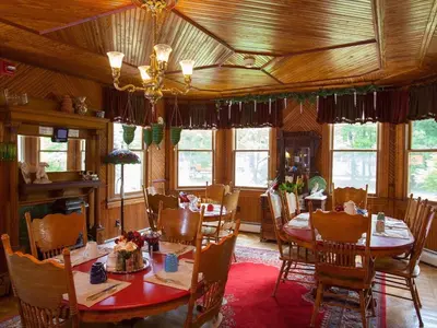 a dining room with tables and chairs and windows at Fairlawn Inn in Hunter