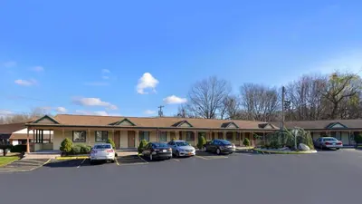 a building with cars parked in a parking lot at Cheshire Welcome Inn in Cheshire