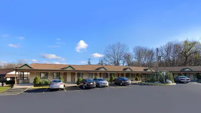 a building with cars parked in a parking lot at Cheshire Welcome Inn in Cheshire