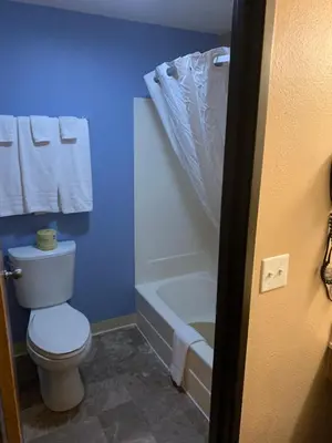 a blue bathroom with a toilet and a bath tub at Super 8 by Wyndham Kingston in Kingston