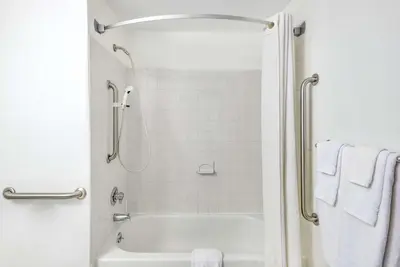 a bathroom with a tub and a shower with towels at Super 8 by Wyndham Kingston in Kingston