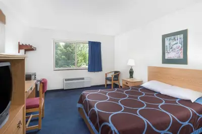 a hotel room with a bed and a television at Super 8 by Wyndham Kingston in Kingston