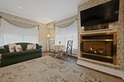 a living room with a fireplace and a green couch at Brook Farm Inn in Lenox