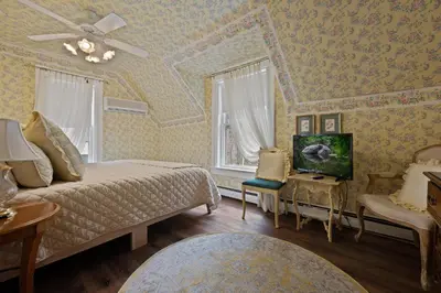 a bedroom with a bed and a couch and a tv at Brook Farm Inn in Lenox