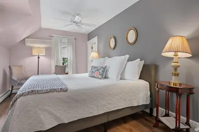 a bedroom with a bed with two lamps and two chairs at Brook Farm Inn in Lenox