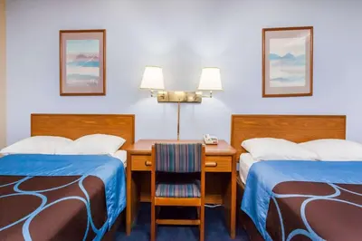 a hotel room with two beds and a desk at Super 8 by Wyndham Sidney NY in Sidney