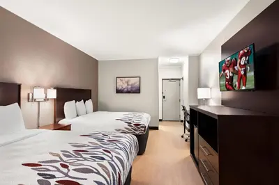 a hotel room with two beds and a desk at Red Roof Inn Norwich in Norwich