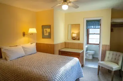 a bedroom with a bed and a chair and a bathroom at Gray Ghost Inn in West Dover