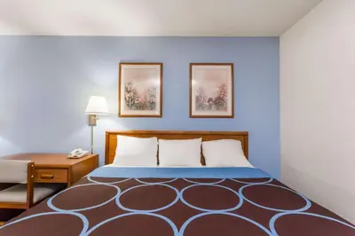 a large bed in a room with a desk and a bed sidx sidx at Super 8 by Wyndham Norwich in Norwich