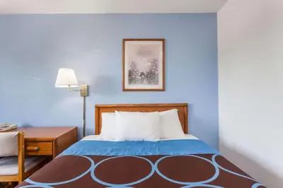 a bedroom with a bed and a desk with a lamp at Super 8 by Wyndham Norwich in Norwich