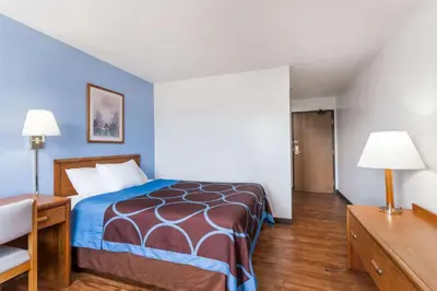 a hotel room with a bed and a desk and lamps at Super 8 by Wyndham Norwich in Norwich