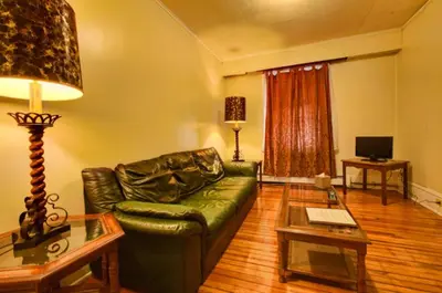 a living room with a green leather couch and a table at Suites on Main in Margaretville