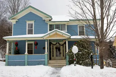 a blue house with christmas wreaths in front of it at Village Suites in Margaretville
