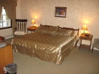 a bedroom with a bed and two chairs and two lamps at Big Bears Lodge in West Dover