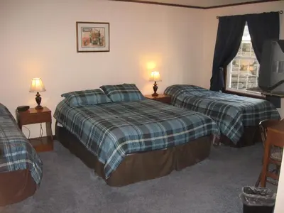two beds in a room with two lamps and a television at Big Bears Lodge in West Dover